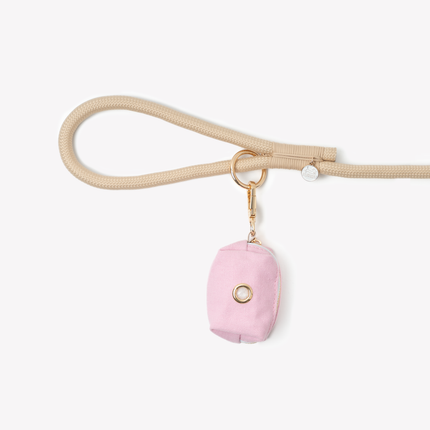 Pink pouch with gold ring on a beige strap against a white background