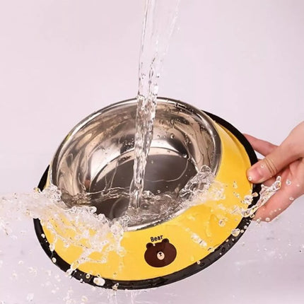 Stainless steel bowl with yellow base being filled with water, showing splashes.