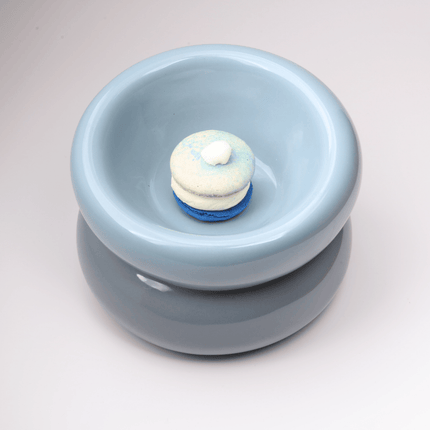 Light blue ceramic bowl with a smaller white and blue treat inside on a light gray background