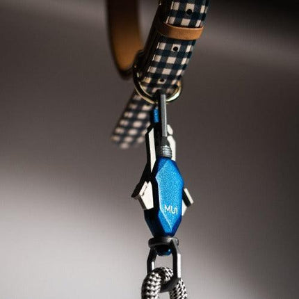 Close-up of a blue carabiner with a checkered strap on a gray background