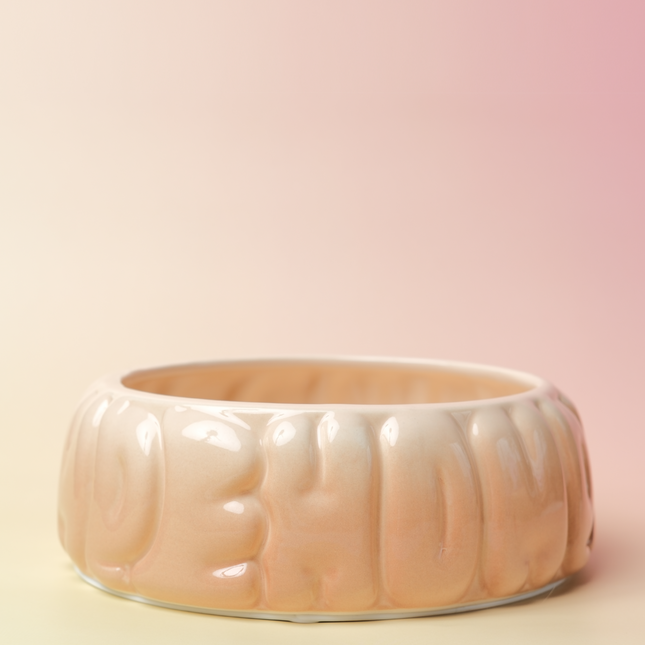 Beige ceramic bowl with textured surface on a pink background