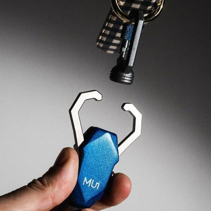 Blue multi-tool keychain held by a hand with a blurred background