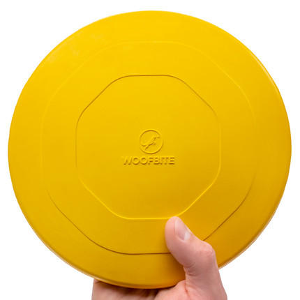Yellow frisbee held by a hand with 'WoofBite' branding on a white background