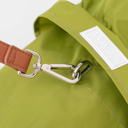 Close-up of a green bag with a brown strap and silver buckle on a white background