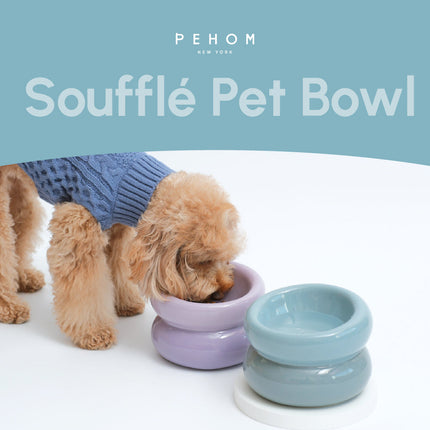 Two dogs with a stack of colorful pet bowls on a white surface, branded 'PEHOM'.