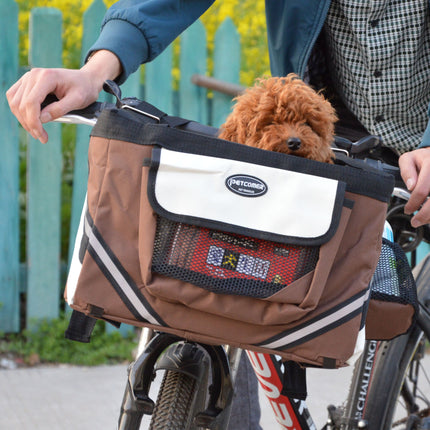 Brown bicycle pet carrier with a dog inside, attached to a bike with a blurred background.