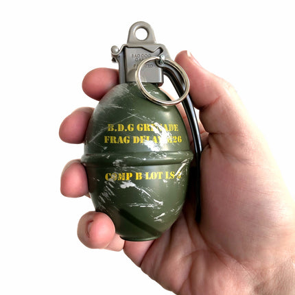Hand holding a green grenade-shaped poop bag holder with text on a white background
