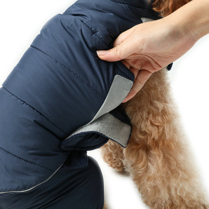 Dog wearing a blue puffer coat with a person adjusting it on a white background