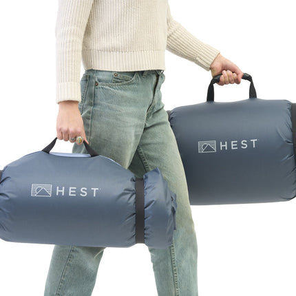 Person holding two HEST pet beds against a white background
