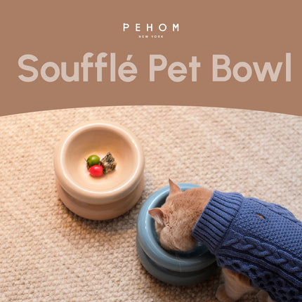 Cat wearing a blue sweater eating from a blue 'Souffle Pet Bowl' with 'PEHOM' branding.