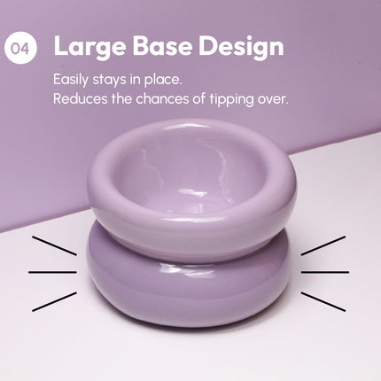 Purple ceramic bowl with large base design on a white surface against a purple background