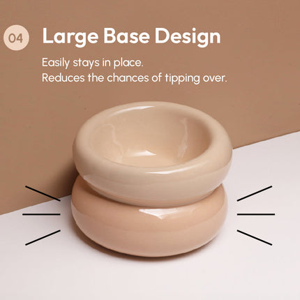A beige ceramic pet bowl on a white surface with text about a large base design.
