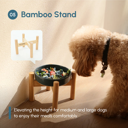 Dog looking at a elevated pet bowl with a bamboo stand on a wooden floor.