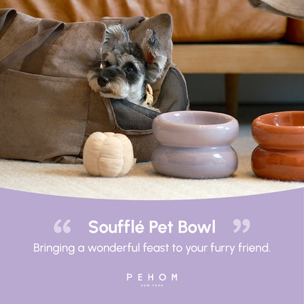 Dog peeking out from a pet bed with two pet bowls and a quote about Souffle Pet Bowl by PEHOM.
