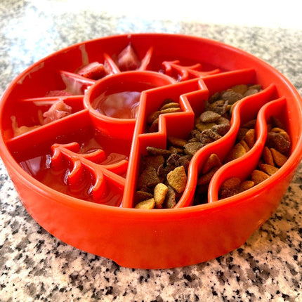 Orange silicone feeding bowl with dry kibble on a granite countertop
