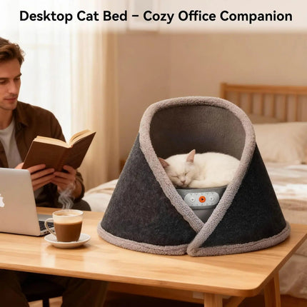 Cat bed on a desk with a person reading a book and a cat sleeping inside it.