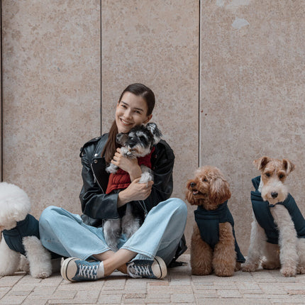 Woman sitting with four dogs in front of a beige wall