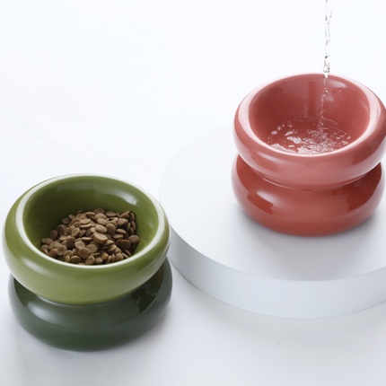 Two ceramic pet bowls, one green and one red, on a white surface.