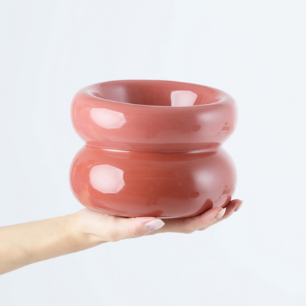 Hand holding a pink ceramic pet bowl against a white background