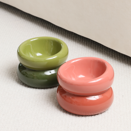two ceramic bowls, green and pink on a textured fabric