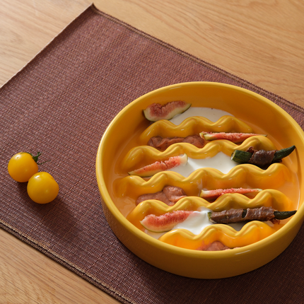 Yellow ceramic pet feeding bowl with wavy design on a brown placemat