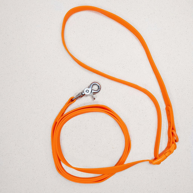 Orange dog leash with a silver clasp on a light gray background