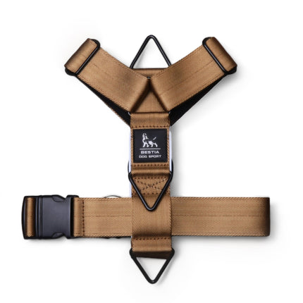 Tan dog harness with black hardware on a white background