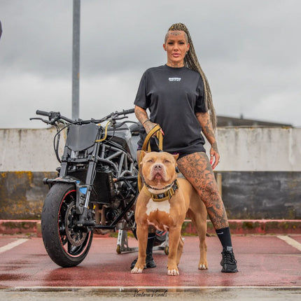 Woman with a tattooed arm standing next to a dog and a motorcycle on a rooftop.