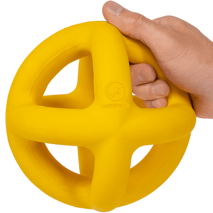 Hand holding a yellow exercise ball with a white background