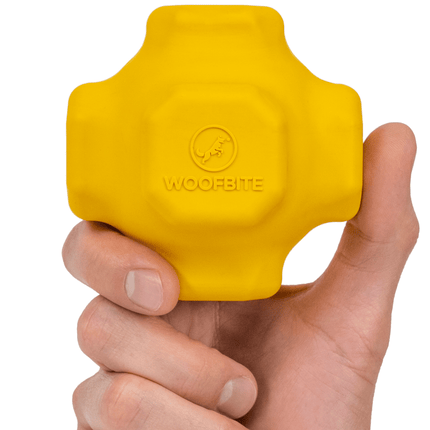 Yellow dog toy with 'WoofBite' branding held in a hand against a white background