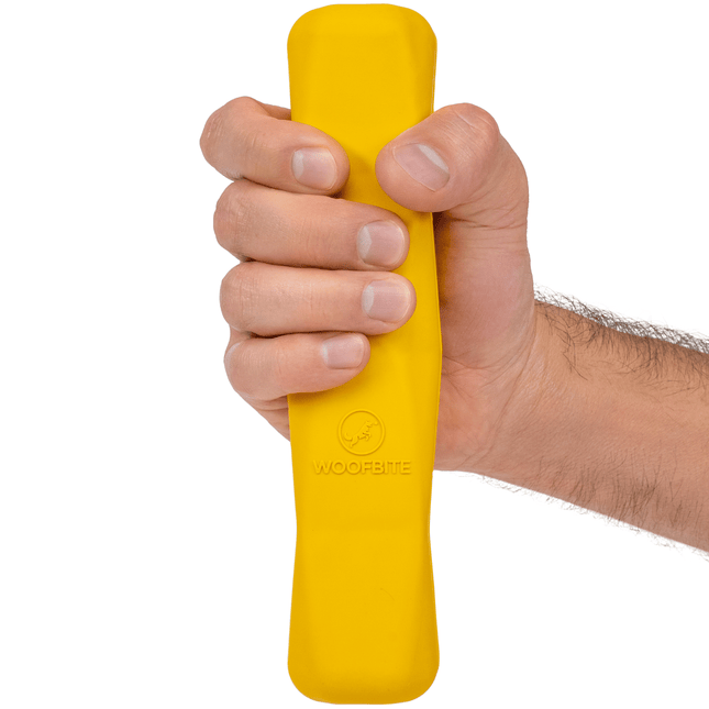 Yellow indestructible dog chew stick held by someone on a white background