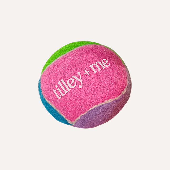 Colorful tennis ball with 'tilley + me' branding on a white background