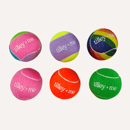 Set of colorful tennis balls with 'tilley + me' branding on a white background