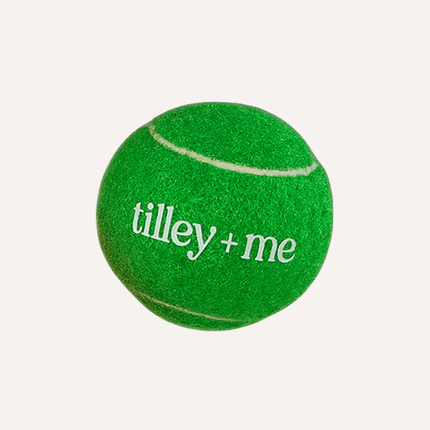 Green tennis ball with 'tilley + me' text on a white background